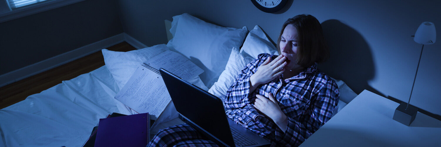 student studying at all hours of the night in bed in their pajamas