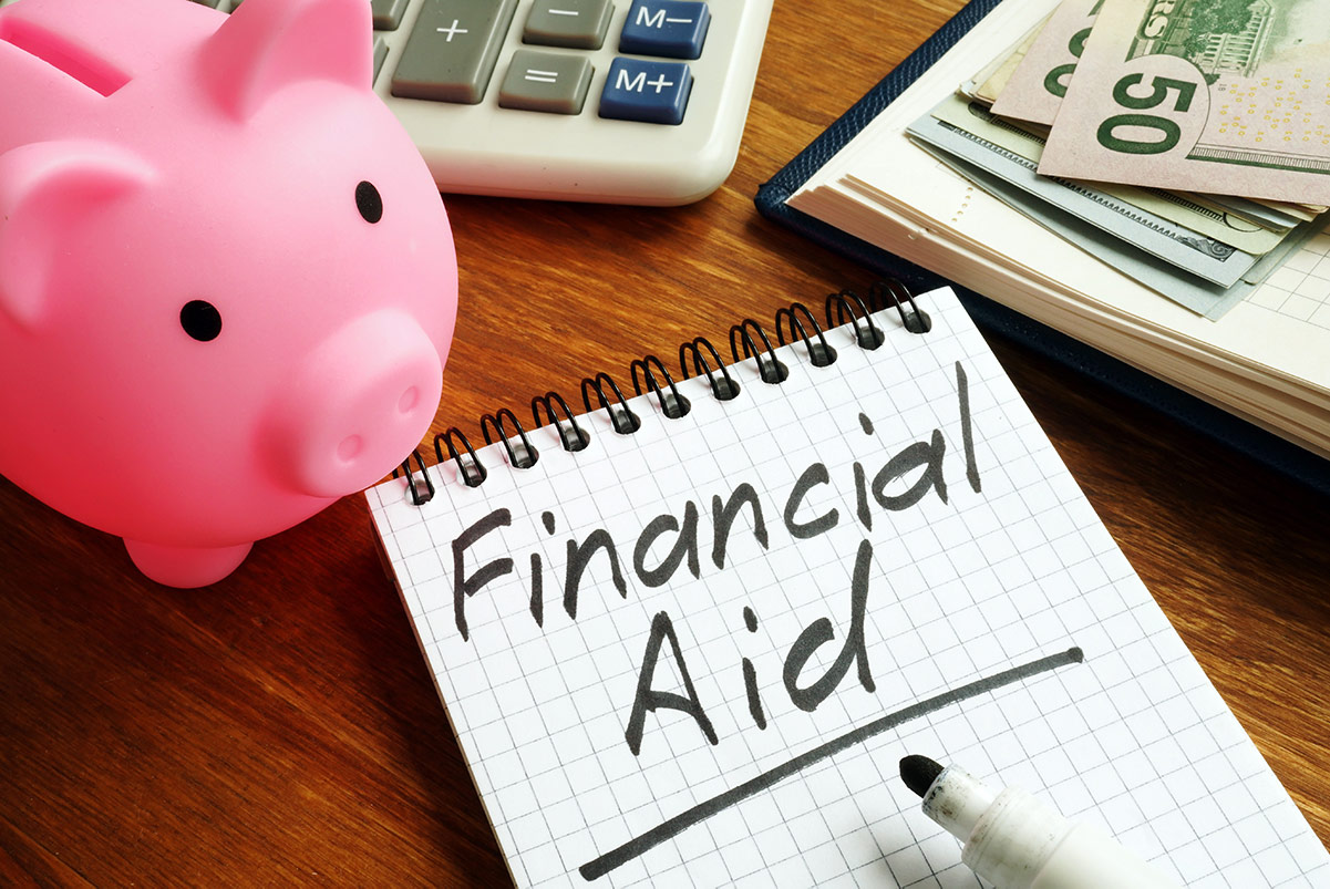 financial aid written on notepad with calculator and piggy bank