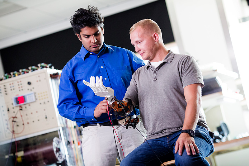 graduate student aiding a client with a robotic prosthetic arm