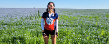 Angela posing in a field with teammate on her Illini 4000 ride across the country
