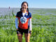 Angela posing in a field with teammate on her Illini 4000 ride across the country