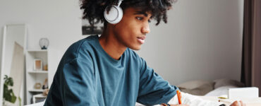 high school student studies with headphones on in their room