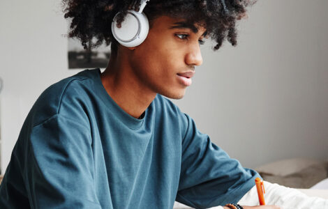 high school student studies with headphones on in their room