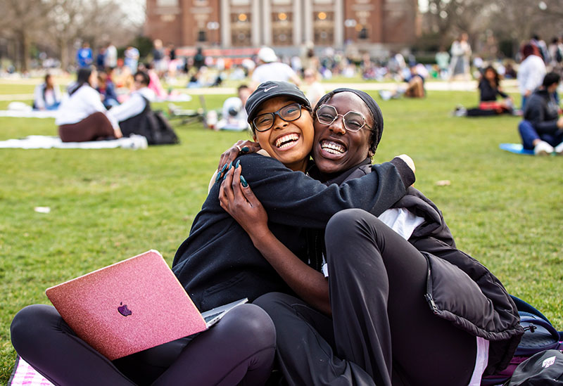 two friends embracing and enjoying some much needed time with one another on the Quad between classes