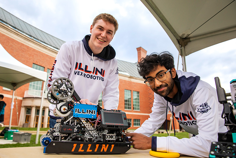 The Illini Vex Robotics team proudly showcases and poses with one of their creations at the Engineering Open House