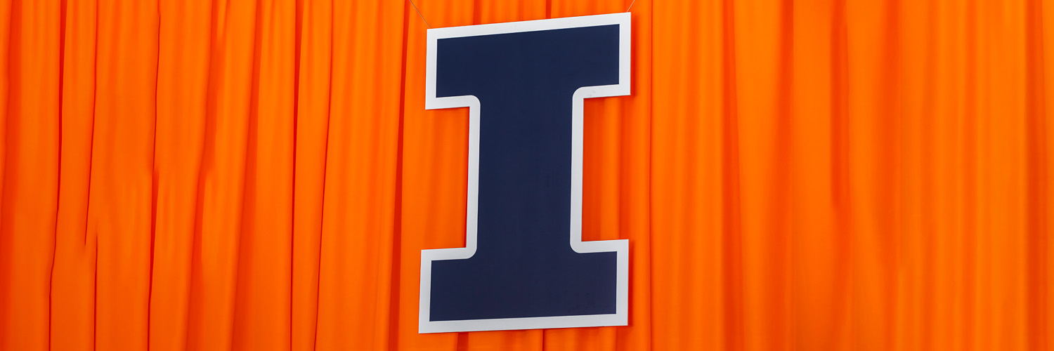 large, blue Block I hanging in front of an orange curtain at Memorial Stadium for Commencement