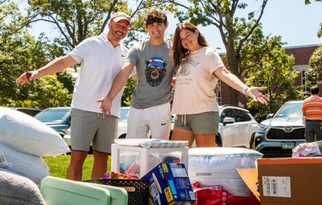 a family posing with their student's stuff they're moving into the dorms during Welcome Week